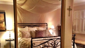 A bedroom with a four-poster canopy bed, a bedside table with a lamp, and a large mirror reflecting the room. - Bayfront - Mission Bay on Sand Panoramic View -Upscale (San Diego)