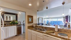 A modern kitchen with granite countertops, white cabinetry, and a view of the ocean. - Bayfront - Mission Bay on Sand Panoramic View -Upscale (San Diego)