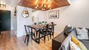 Un comedor con techo de madera, un espejo redondo y un cuadro enmarcado en la pared.