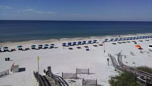 A beach with rows of sun loungers and umbrellas, a wooden boardwalk, and a clear view of the ocean. - Gulf Beachfront: Beautiful Luxury West Corner Unit, Wrap-Around Balcony! (Gulf Shores)