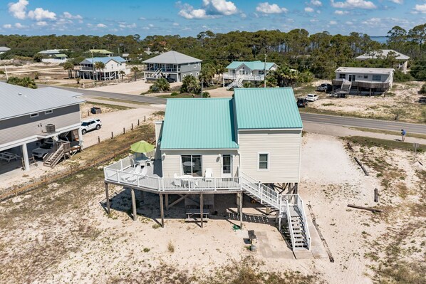 A beachfront house with a green roof, a balcony, and a dock. - 100 Steps to the Gulf -Soaring Ceilings, Beams, Contemp, Free Lighthouse Passes (Saint George Island)