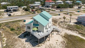 Et hus ved stranden med balkon og udendørs siddeplads.