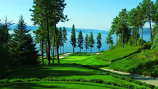 Un campo de golf con vistas despejadas al agua y montañas a lo lejos.