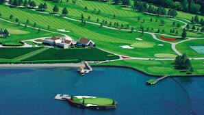 Un campo de golf con un club de campo, un embarcadero y una masa de agua.