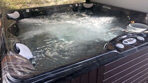 Un jacuzzi con terraza de madera y vista a árboles a través de una malla.