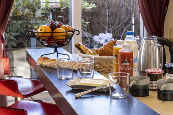 A breakfast table with fruits, bread, butter, and beverages.