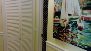 A hallway with a white door and a painting of sailboats on the wall.