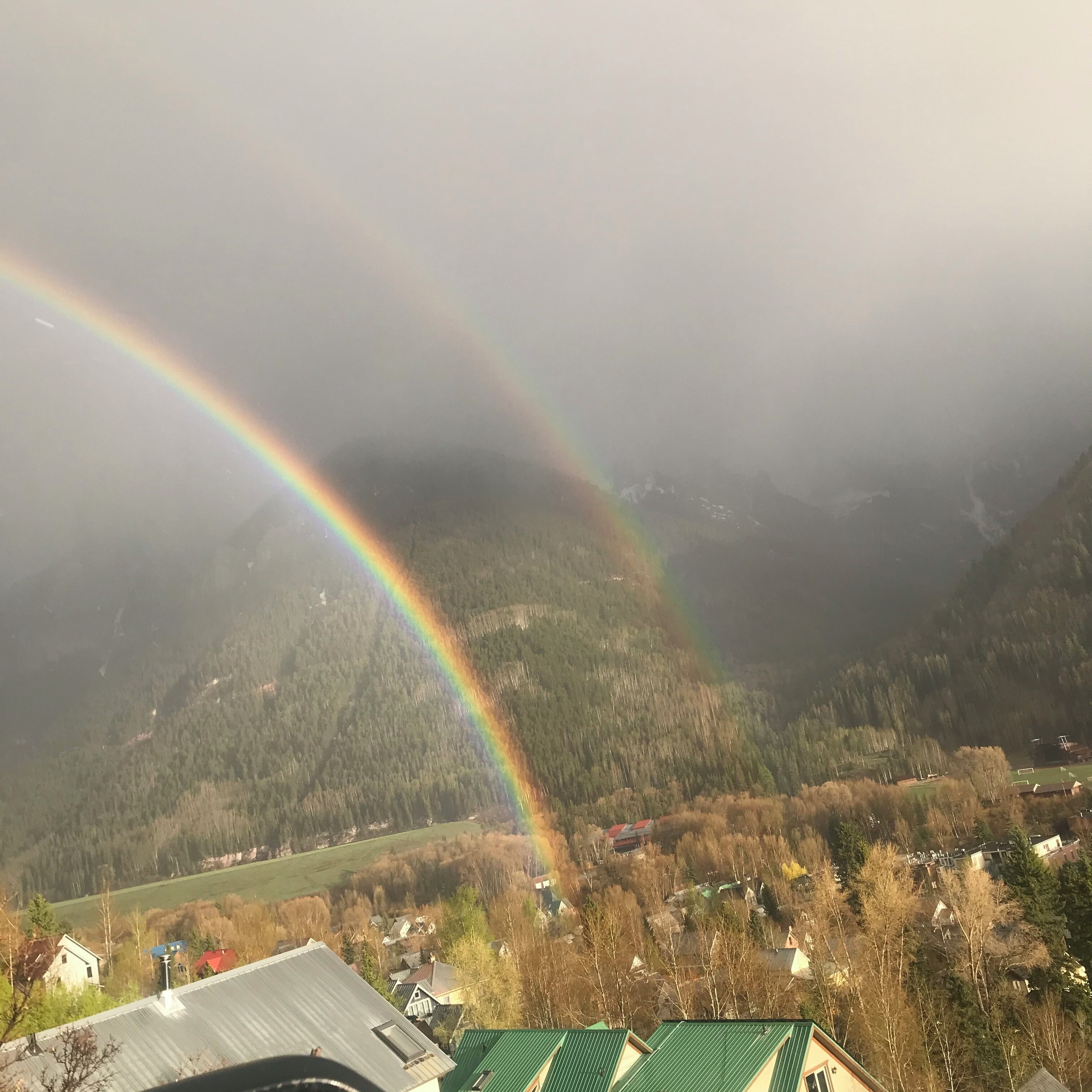 Un paysage de montagne avec un arc-en-ciel au-dessus d’une vallée.