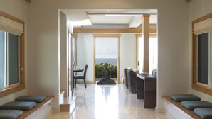 A spacious hallway with a view of the sea, a meditation area with cushions, and a seating area with a view. - Hale Pono- Oceanfront, private, gated, great views, AC, large property  (Haleiwa)