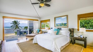 A spacious bedroom with a large bed, a ceiling fan, and a view of the ocean through a sliding glass door. - Hale Pono- Oceanfront, private, gated, great views, AC, large property  (Haleiwa)