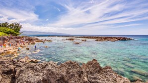 A rocky beach with clear turquoise water and a view of distant mountains. - Hale Pono- Oceanfront, private, gated, great views, AC, large property  (Haleiwa)