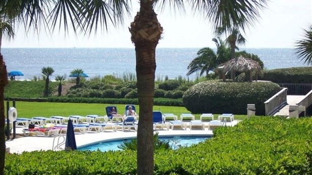 A pool area with lounge chairs and a view of the ocean. - St. Simons Island Beach Club Condo #126 (St. Simons Island)