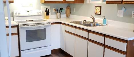 A kitchen with white cabinets, a stove, and a sink.