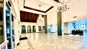 A spacious lobby with a herringbone floor pattern, large columns, and a chandelier. - No Resort Fee~Gulf Front Double Balcony~Free Resort Chairs~Reserved Parking Spot (Panama City Beach)