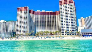 A high-rise hotel with multiple balconies, a beach in the foreground, and clear blue skies. - No Resort Fee~Gulf Front Double Balcony~Free Resort Chairs~Reserved Parking Spot (Panama City Beach)