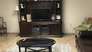 Un soggiorno con un mobile TV in legno scuro, una TV a schermo piatto, divani in pelle e un tavolino da caffè.