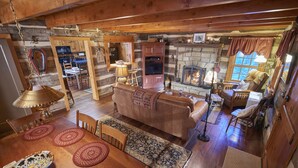 Un acogedor interior de cabaña con comedor, sala de estar con chimenea y cocina.