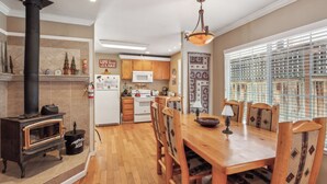Una cocina con estufa de leña, microondas y mesa de madera con sillas.