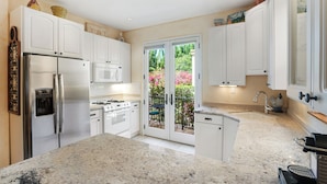 A modern kitchen with white cabinets, stainless steel appliances, and a large island. - Secret Getaway — 2 blocks to the Beach and Funk Zone (Santa Barbara)