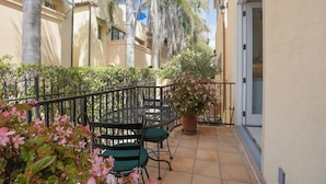 A patio with a round table and chairs, surrounded by a black metal fence, and a potted plant with pink flowers. - Secret Getaway — 2 blocks to the Beach and Funk Zone (Santa Barbara)