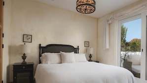 A bedroom with a large bed, two bedside tables with lamps, a ceiling light fixture, and a view through a window. - Secret Getaway — 2 blocks to the Beach and Funk Zone (Santa Barbara)