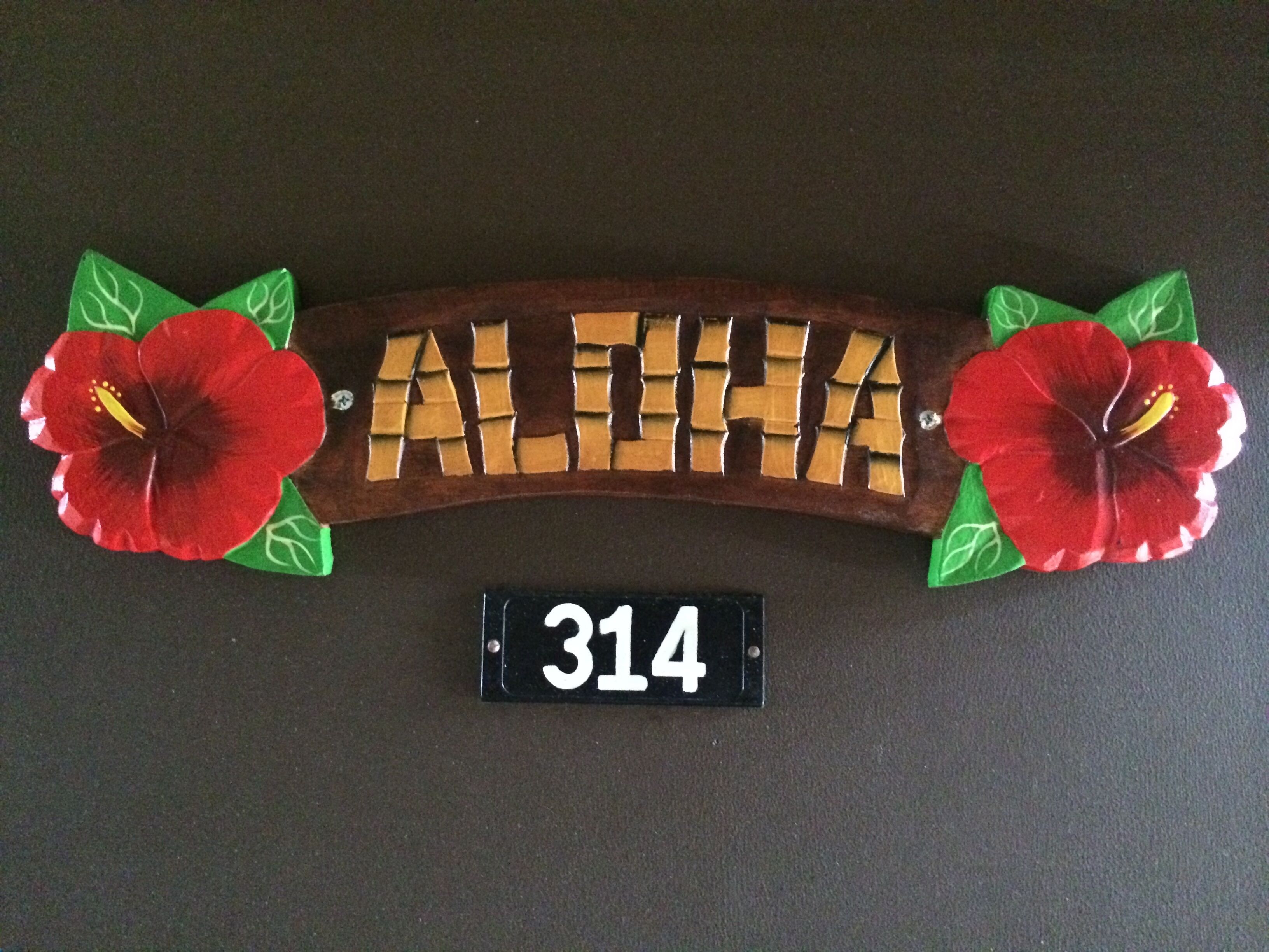Une enseigne en bois portant le nom « ALHIA » et le numéro « 314 » en dessous.