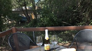 An outdoor dining area with a table set for two, featuring plates, cutlery, a bottle of champagne, and a fruit platter. - Beverly beach delight (Newport)