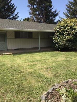 A residential building with a covered porch, a grassy yard, and a large tree. - Beverly beach delight (Newport)