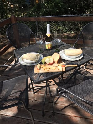 A table set outdoors with a bottle of lemonade, plates of food, and cut apples. - Beverly beach delight (Newport)