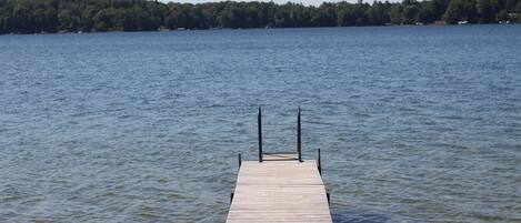 A wooden dock extending into a calm lake with a forested shoreline in the background.