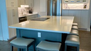 A modern kitchen with a large island, bar stools, pendant lighting, and stainless steel appliances. - Spacious Oceanfront Condo in Palmetto Dunes, Unobstructed Ocean Views  (Hilton Head Island)