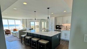 A modern kitchen with a large island, bar stools, and a view of the ocean. - Spacious Oceanfront Condo in Palmetto Dunes, Unobstructed Ocean Views  (Hilton Head Island)