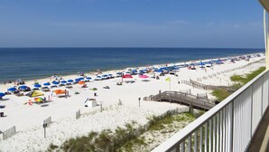 Een strand met parasols en strandstoelen, een houten looppad en uitzicht op de oceaan.
