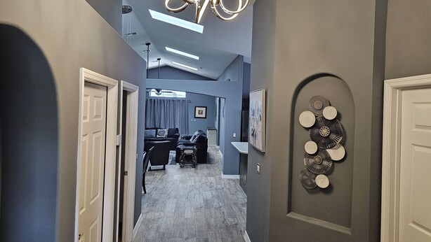 Um corredor com design moderno no teto, área de jantar com mesa e cadeiras, e um elemento decorativo na parede.