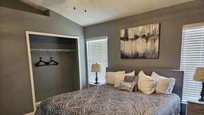 Um quarto com uma cama grande, um closet espaçoso e um quadro na parede.