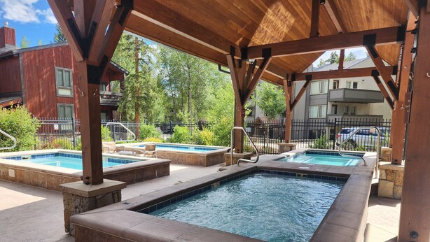 An outdoor pool area with multiple hot tubs and a covered seating area. - Cozy unit walking distance to Quick Silver Ski Lift and free parking. (Breckenridge)