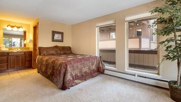 A bedroom with a large bed, a bathroom with a vanity, and a sliding glass door to a balcony.