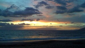 Escena de playa con un atardecer sobre el océano.