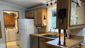 Une cuisine avec des meubles en bois, un réfrigérateur blanc, un lave-vaisselle et un plan de travail en bois doté d’un évier.