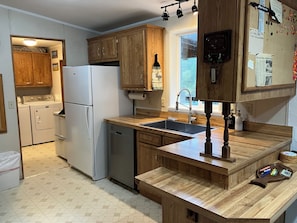 A kitchen with wooden cabinets, a white refrigerator, a dishwasher, and a wooden countertop with a sink.