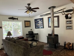 A living room with a sofa, a table, a chair, a fireplace, and a ceiling fan.