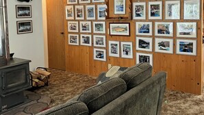 Une pièce avec un mur en bois, un ventilateur de plafond, une cheminée et un canapé.