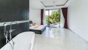 A modern bathroom with a bathtub, a shower, and a large mirror. There is a bed with a view of the outdoors through a sliding glass door. - 3 Bedroom Sea View Villa 2 - Chaweng Noi SDV162-By Samui Dream Villas (Koh Samui)