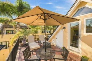 Un patio con mobiliario exterior, una mesa y una sombrilla.