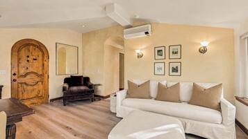 Ein Wohnzimmer mit einer Holztür, einem braunen Ledersofa, einem weißen Sofa und einem Holztisch.