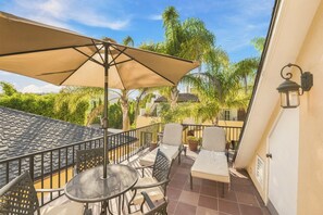 Una terraza con mobiliario exterior, una sombrilla grande y vistas a zonas verdes y edificios.