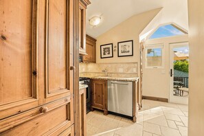 A kitchen with wooden cabinets, a stainless steel dishwasher, and a tiled backsplash.