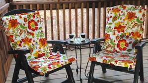 A wooden deck with two chairs and a small table, all with floral upholstery.