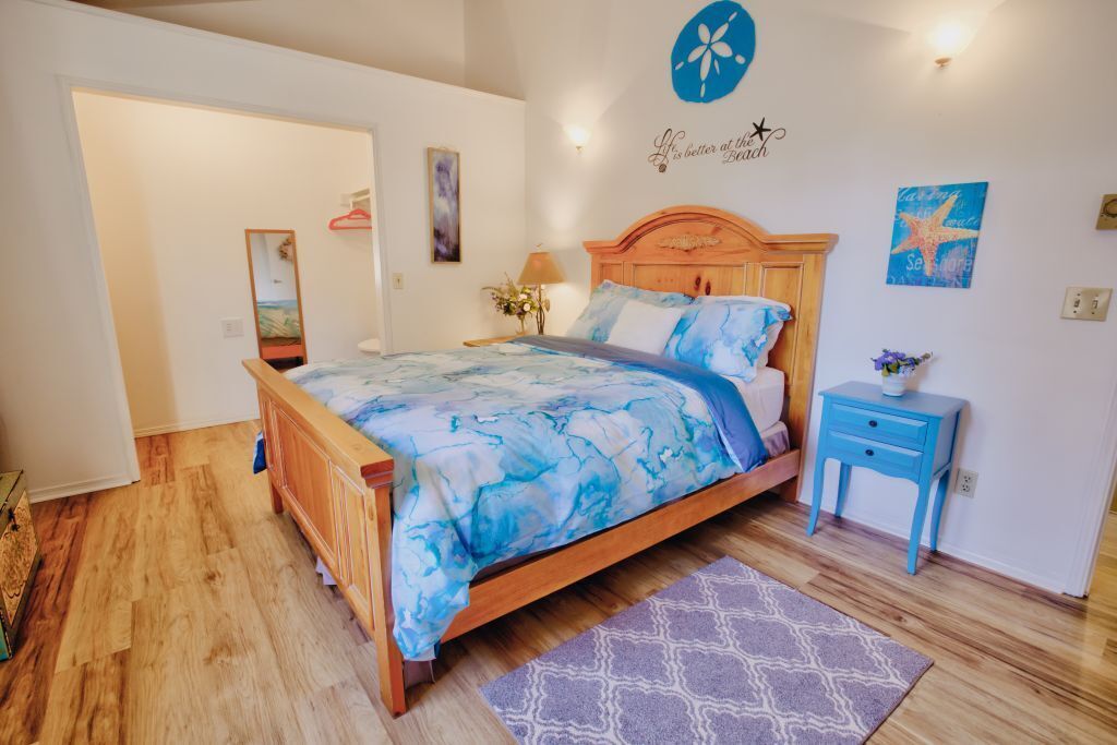 Ein Schlafzimmer mit einem hölzernen Bett, einem Nachttisch, einem Spiegel und Wandbildern.