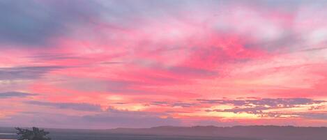 A sunset over a flat landscape with a body of water reflecting the sky.